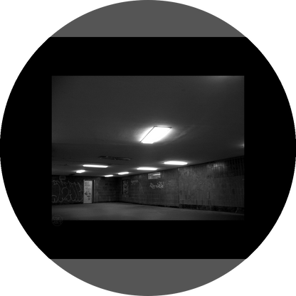un4rt - a black and white photographie of a former underground trespas that once was part of the train station "alexanderplatz" in berlin. the image shows a corner with a closed door. graffities on the wall. one lamp on the ceiling is broken.