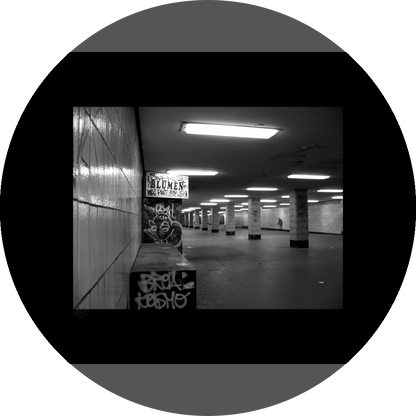 un4rt - a black and white photographie of a former underground trespas that once was part of the train station "alexanderplatz" in berlin. tiled square columns support the ceiling. the left wall also has a porch of an old flower shop. the porch is full of graffities and the sign of the shop advertises "blumen".