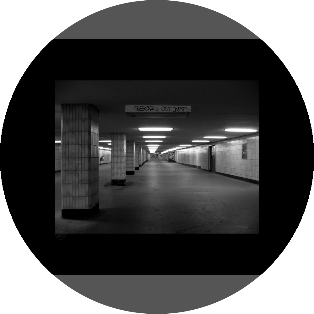 un4rt - a black and white photographie of a former underground trespas that once was part of the train station "alexanderplatz" in berlin. tiled square columns support the ceiling. a closed door on the right side. one light on the ceiling does´t work.