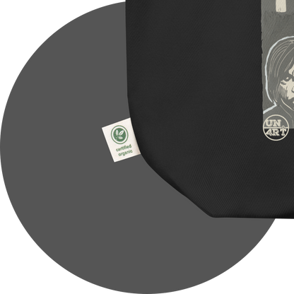 un4rt - the image shows details of a black cotton tote bag with parts of a print. a white label is attached to the tote bag. the print n the label reads: "certified organic".