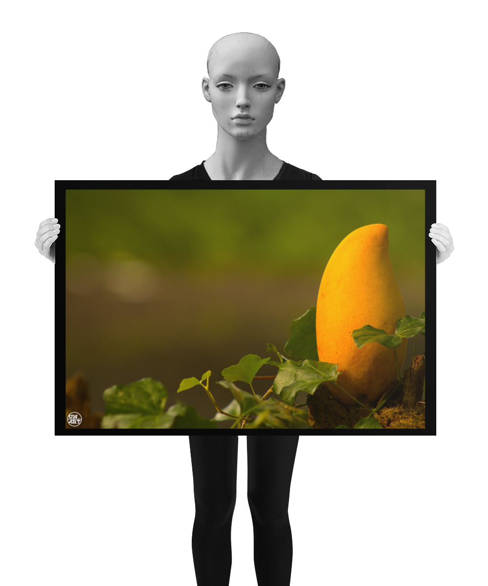 un4rt - photographie of a yellow mango in a forest. the mango is placed on top of a rotten tree trunk. some ivy around the mango. blurry and defocused background. the poster is presented by a mannequin in black and white.