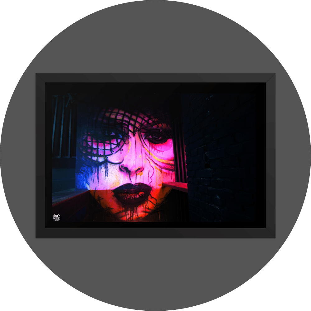 un4rt - the photographie shows a mural of a female face in various colors, pink, yellow, blue, orange. the face is surrounded by black walls, some made of bricks, some made of wood. 