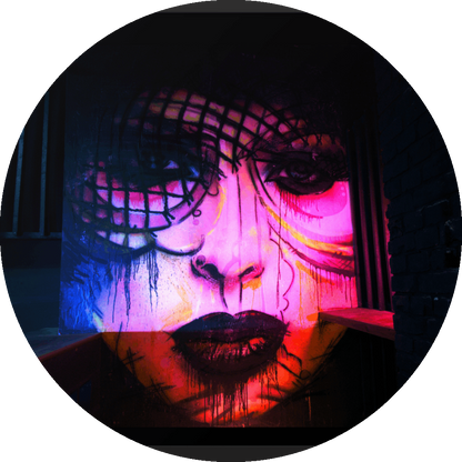 un4rt - the photographie shows a mural of a female face in various colors, pink, yellow, blue, orange. the face is surrounded by black walls, some made of bricks, some made of wood. 