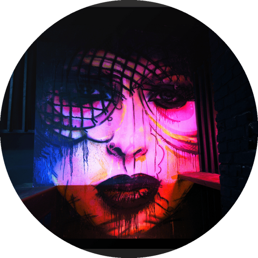 un4rt - the photographie shows a mural of a female face in various colors, pink, yellow, blue, orange. the face is surrounded by black walls, some made of bricks, some made of wood. 