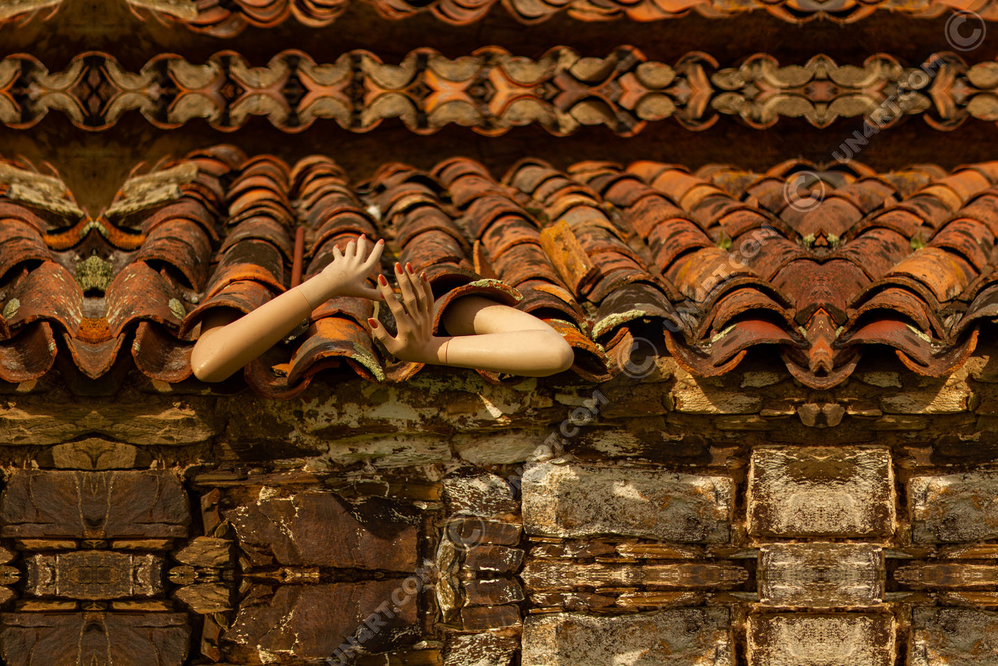 un4rt - a photographie that is mirrored on all sides. the image shows an old roof with arms coming out of the roof tiles. front view. ancient stone wall with big stones under the roof.