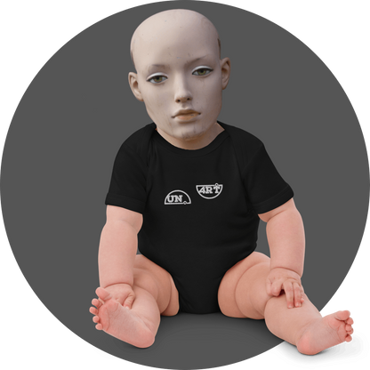 UN4RT black baby bodysuit, small white "UN." semicircle logo and "4RT" semicircle logo side by side on chest, short sleeve, snap closure, baby mannequin seated front view, grey circular background.