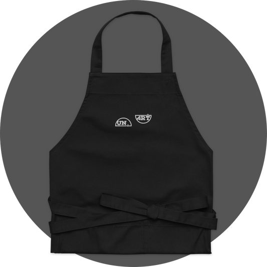 un4rt - the images shows a black apron with white embroidery of a splitted "UN4RT"-logo. 