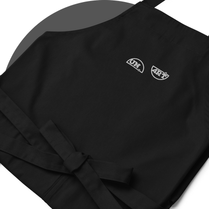 un4rt - the images shows details of a black apron with white embroidery of a splitted "UN4RT"-logo. 